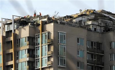 　　昨日，身穿橘黃色馬甲的工作人員在人濟(jì)山莊樓頂拆除違章建筑。新京報(bào)記者 吳江 攝