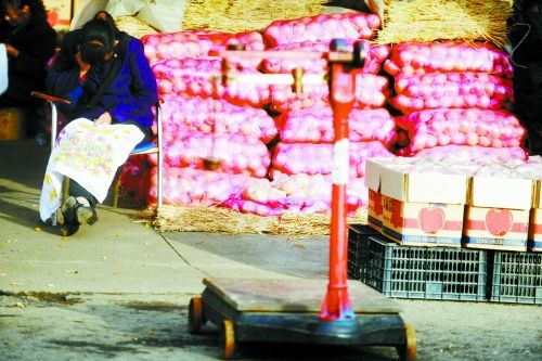 水果批發(fā)市場(chǎng)內(nèi)，沒有客戶時(shí)，商戶在繡十字繡