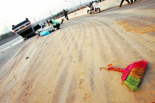 被撞的環(huán)衛(wèi)工躺在地上，身上蓋著藍(lán)色布塊，現(xiàn)場除散落的汽車碎片外，還留有被撞斷的掃帚。