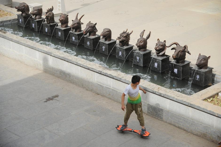 圖為一名市民從獸首旁經(jīng)過。