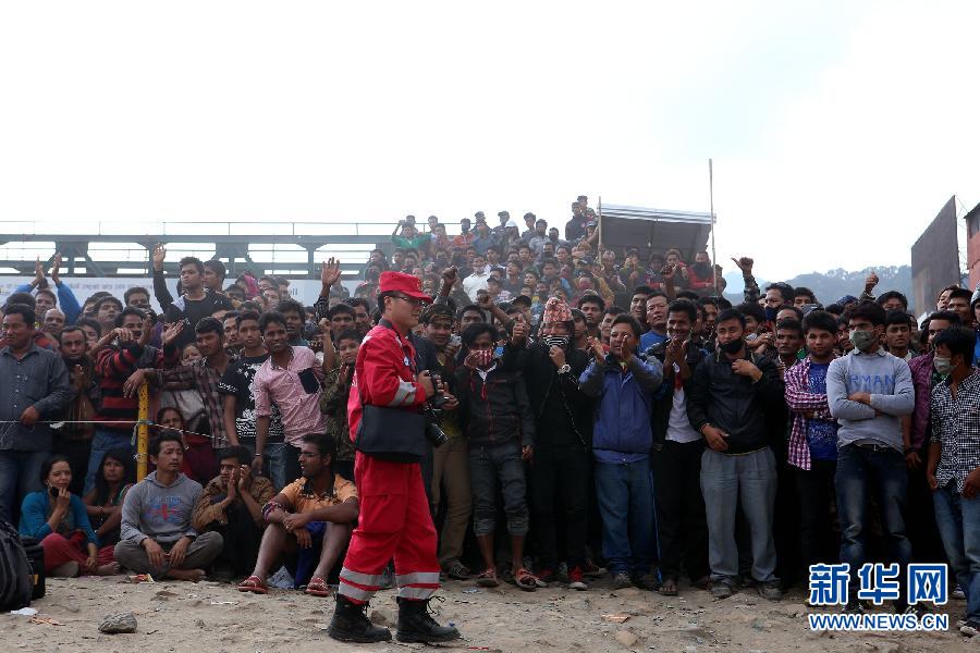 圍觀的尼泊爾民眾在中國(guó)國(guó)際救援隊(duì)成功搜救出幸存者后向搜救隊(duì)員歡呼致意。