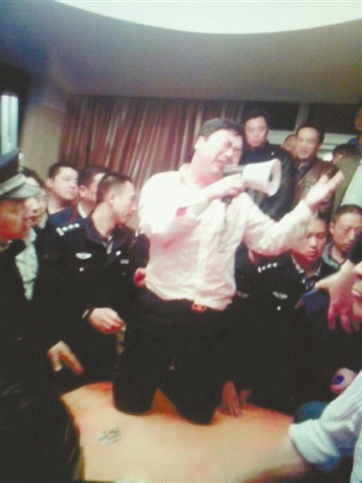 　4月19日，泰州市濱江工業(yè)園區(qū)管委會招待中心，一男子跪在酒桌上喊話求饒。李根 攝