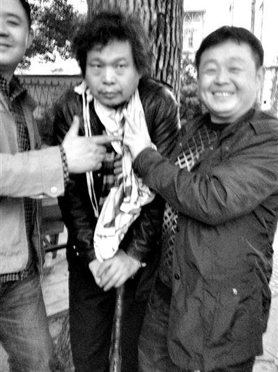 兩名接訪人員與患有癌癥的訪民段新德合影時，面帶笑容擺出勝利的手勢。