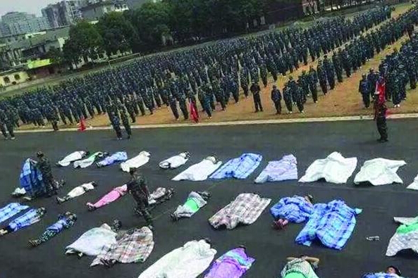 20多名女生躺在瀝青跑道上，身上嚴嚴實實地裹著棉被，接受太陽的照曬。