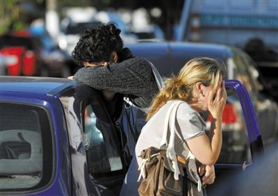 27日，遇難者親友在火災現(xiàn)場旁哭泣。