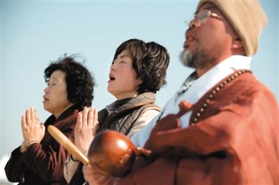 23日，一名僧侶引領人們?yōu)樗勒咂矶\。