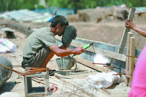 　正午陽光下，工地上的焊接工人還在認真工作。