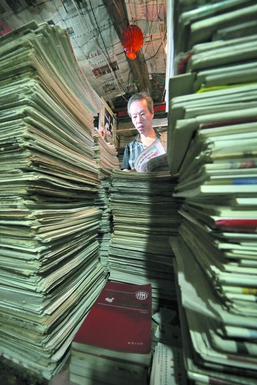 王曉民坐在寫字桌前，被報(bào)紙淹沒(méi)。