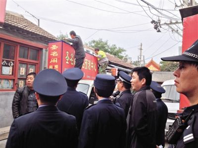 昨日下午,東城區(qū)工商、城管、公安等部門,對(duì)雍和宮附近的預(yù)測(cè)中心進(jìn)行清理整頓,站在車頂?shù)膬擅と苏鸪患摇邦A(yù)測(cè)中心”的招牌。因雍和宮、白云觀等文化景點(diǎn)外聚集大量算命先生,被媒體稱為“算命一條街”。本版攝影/新京報(bào)記者 李寧 攝