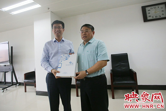 阿里云計算總裁胡曉明向河南省新聞出版廣電局局長朱夏炎遞交《中原云平臺交付手冊》。