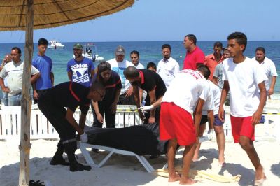 6月26日，在突尼斯蘇塞，救生員和醫(yī)務(wù)人員在發(fā)生襲擊事件的海灘運(yùn)送一名死者的遺體。新華社發(fā)