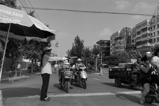 昨日，開封市區(qū)一名協(xié)管員在指揮群眾過馬路