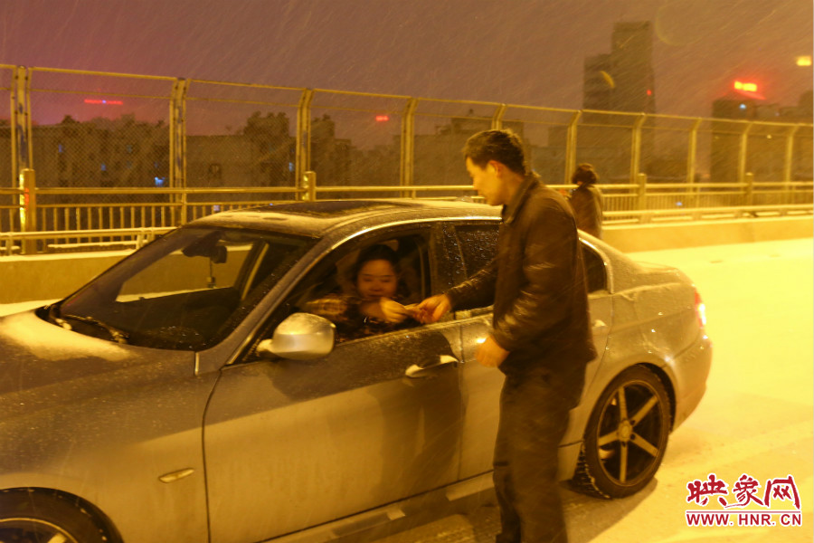 “推車人”幫助一輛車上坡后，收取“勞務(wù)費”。