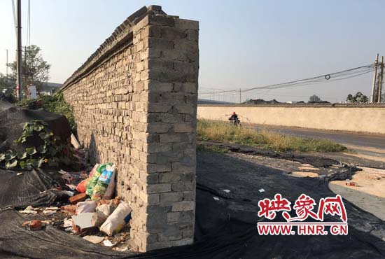 一墻之隔，一邊是道路，一邊是垃圾和荒草，市民質(zhì)疑其為遮羞墻。