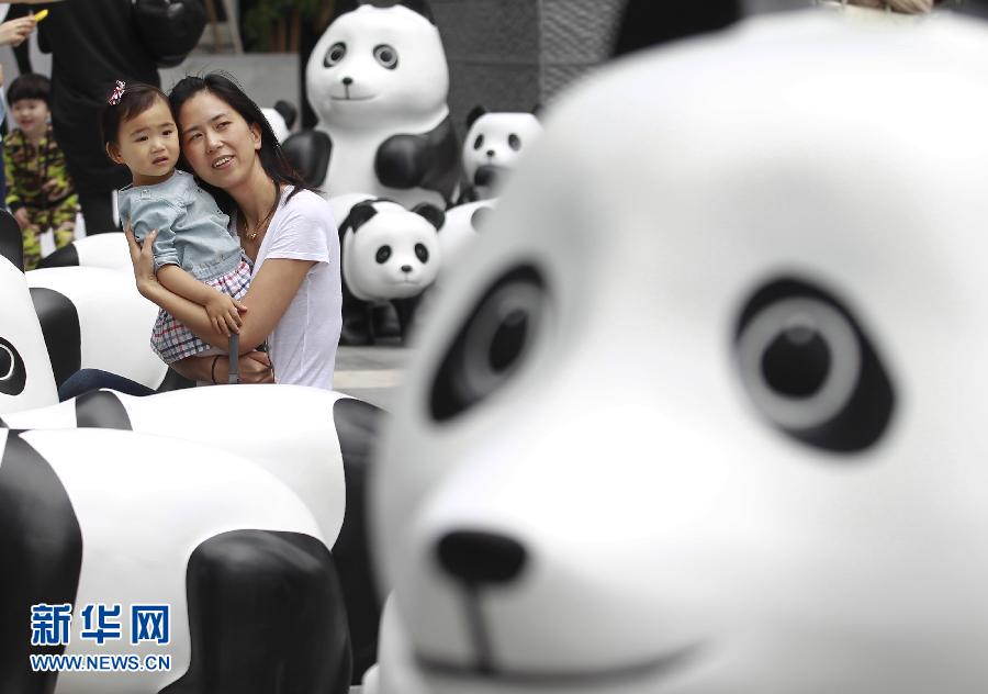 6月2日，一位家長帶著孩子在上海街頭和大熊貓模型合影。