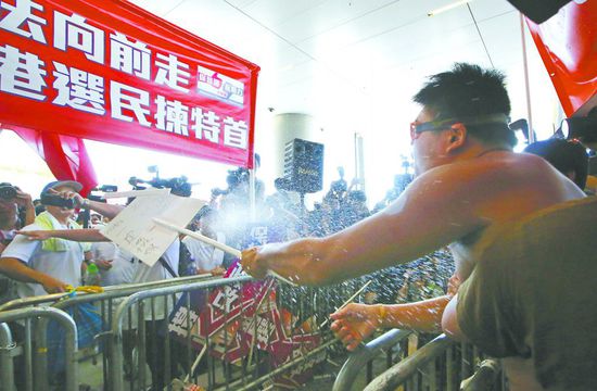 17日，在香港立法會外，一名反對政改的男子向支持派人群投擲標(biāo)牌。