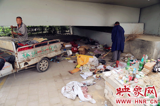 負(fù)責(zé)高架橋下綠化的人員在清理流浪漢留下的垃圾和雜物。