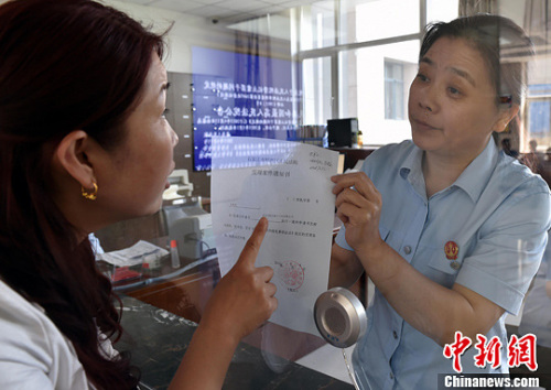 資料圖：2015年5月4日，河北石家莊市橋西區(qū)人民法院立案庭庭長(zhǎng)齊燕正在為立案人辦理相關(guān)手續(xù)，完成整個(gè)過程只用了5分鐘。當(dāng)日是立案登記制改革首個(gè)工作日，該院共立案36件，立案率達(dá)到90%。中新社發(fā) 翟羽佳 攝