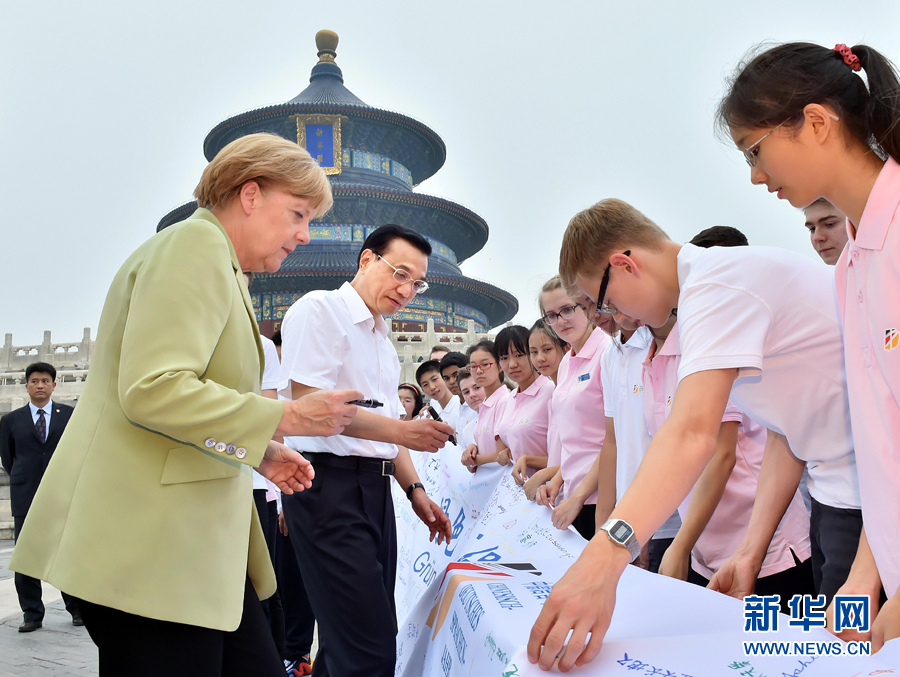 李克強(qiáng)同默克爾在紀(jì)念橫幅上簽名。