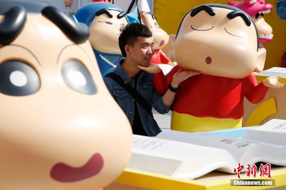4月22日，游客與蠟筆小新合影?！跋灩P小新25周年紀(jì)念特展”日前在北京開展，吸引了不少市民游客。
