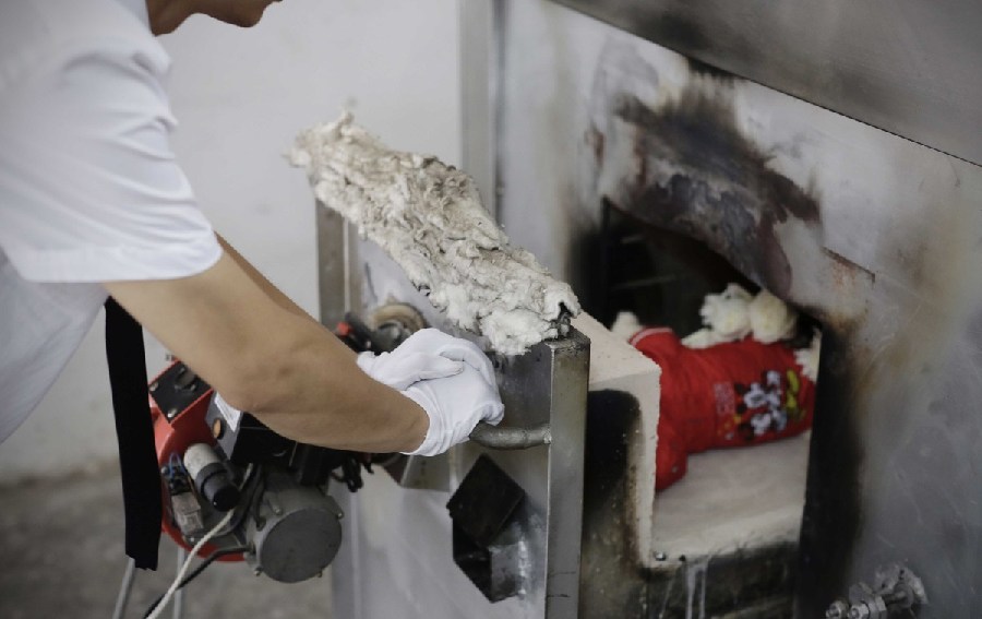 工作人員將狗狗推入火化爐。