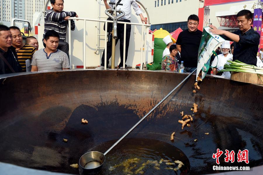 工作人員向大鍋內(nèi)加入油和姜等烹飪調(diào)料。 圖片來源：CFP視覺中國(guó)