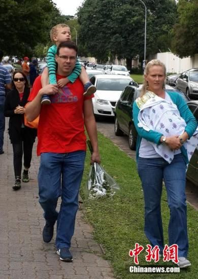圖為一個白人家庭，由父母帶著孩子到曼德拉家門外悼念。中新社發(fā) 宋方燦 攝