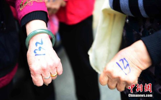 圖為10月28日，在江西九江市一家羊絨皮草服裝服飾博覽會現(xiàn)場，老人們正在頂著寒風排隊等待領取10元代金劵。