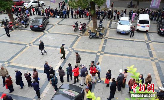 圖為10月28日，在江西九江市一家羊絨皮草服裝服飾博覽會現(xiàn)場，老人們正在頂著寒風排隊等待領取10元代金劵。