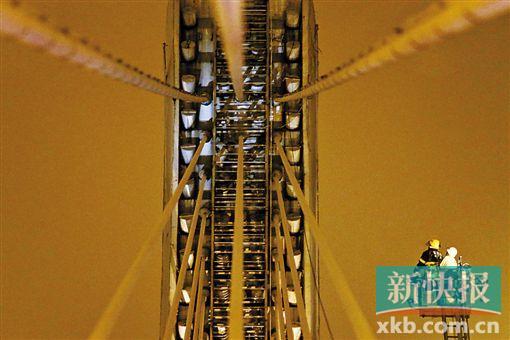 截至今日零時(shí)，男子仍未有下橋舉動(dòng)。圖為公安和消防人員乘消防云梯在高空上和男子交談。